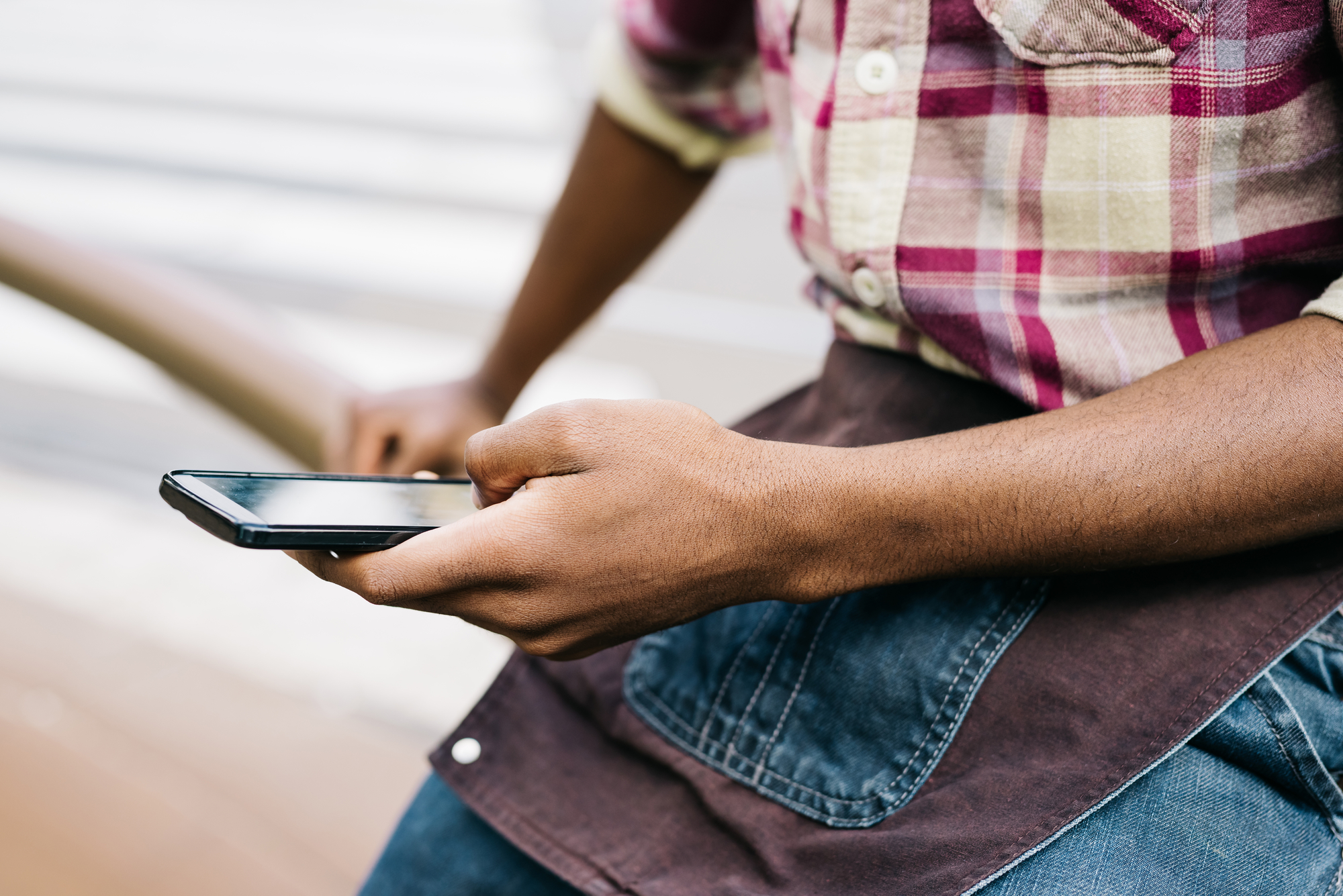 Close up on the hand of a young handsome afro black man using a smartphone, tapping the screen - technology, social network, communication concept